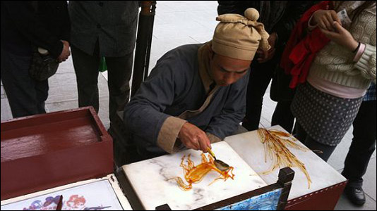 A worker at the Hangzhou theme park makes candy in the shape of a horse.