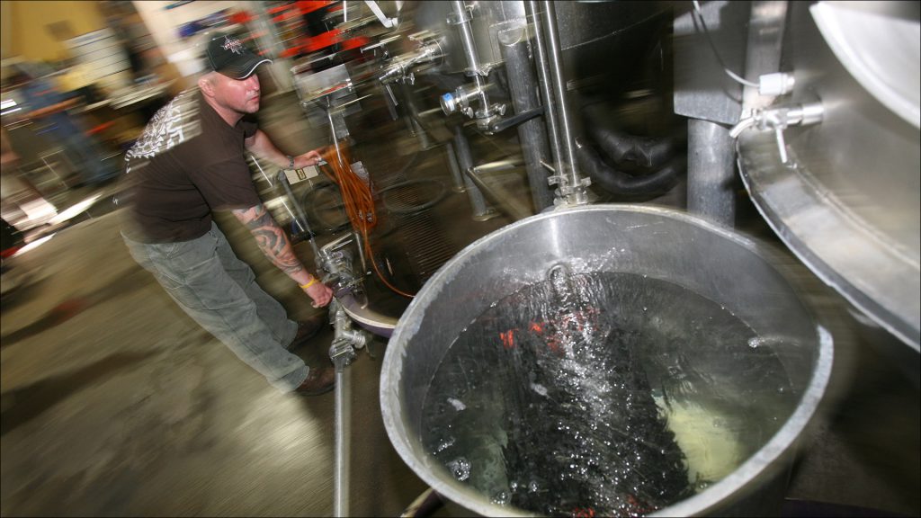 Sun King's Adrian Ball cleans out lines and brewing tanks with fresh water and a cleaning agent.