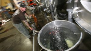 Sun King's Adrian Ball cleans out lines and brewing tanks with fresh water and a cleaning agent.