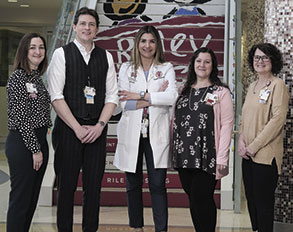 Five members of Riley Children's Health's Fetal Center posed in front of a staircase painted with the Riley Children's Health logo.