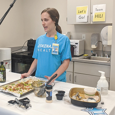 Mariah Adams, a registered dietitian at Eskenazi Health, leading a virtual class from a kitchen island with a sheet pan of vegetables in front of her