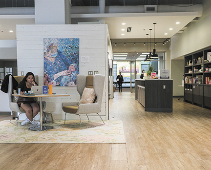 Photo of a contemporary designed workspace with light colored wood plank floors, white subway tile walls, and minimalist wingback chairs ar a square table