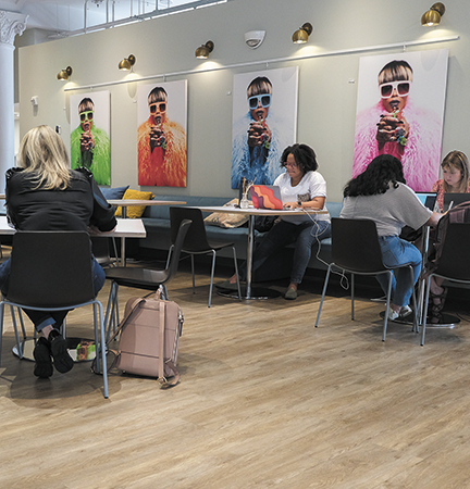 Photo of a cafe style workspace with light colored wood plank floors and many work tables