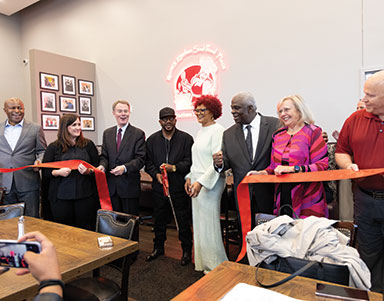 A ribbon cutting ceremony with several smiling people standing behind a recently cut red ribbon