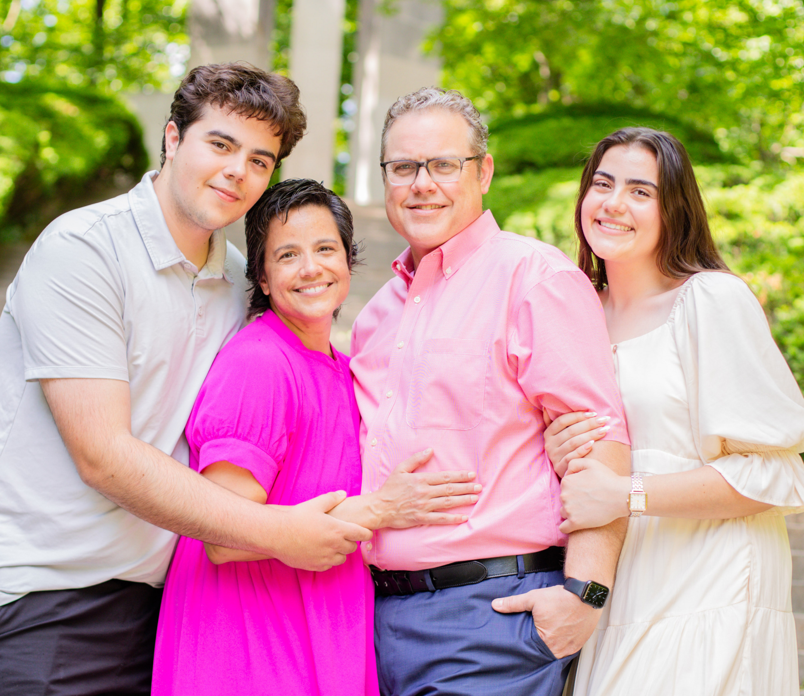 A family of four gathered close smiling at the camera