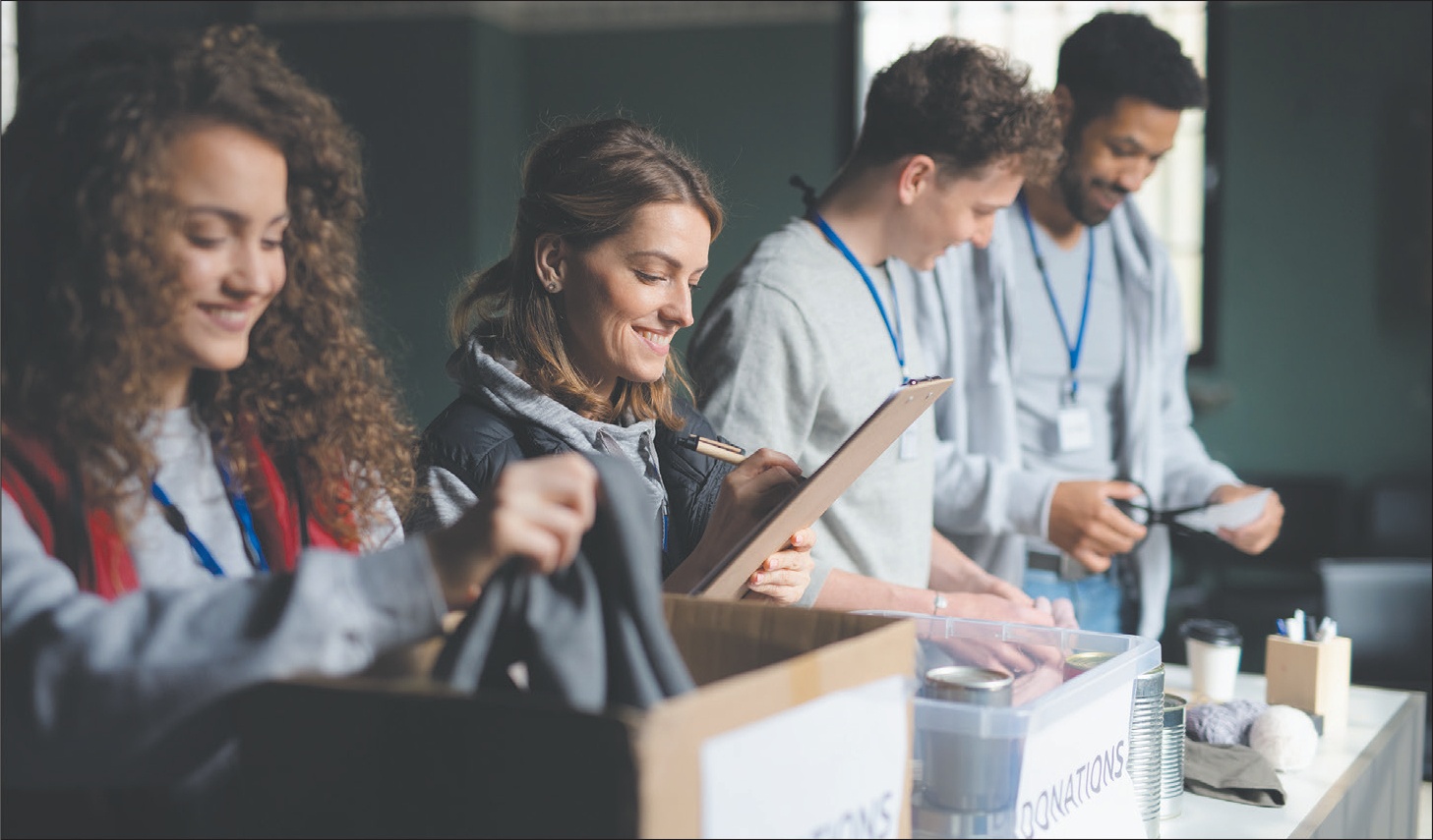 Four smiling volunteers work at a table to process donations