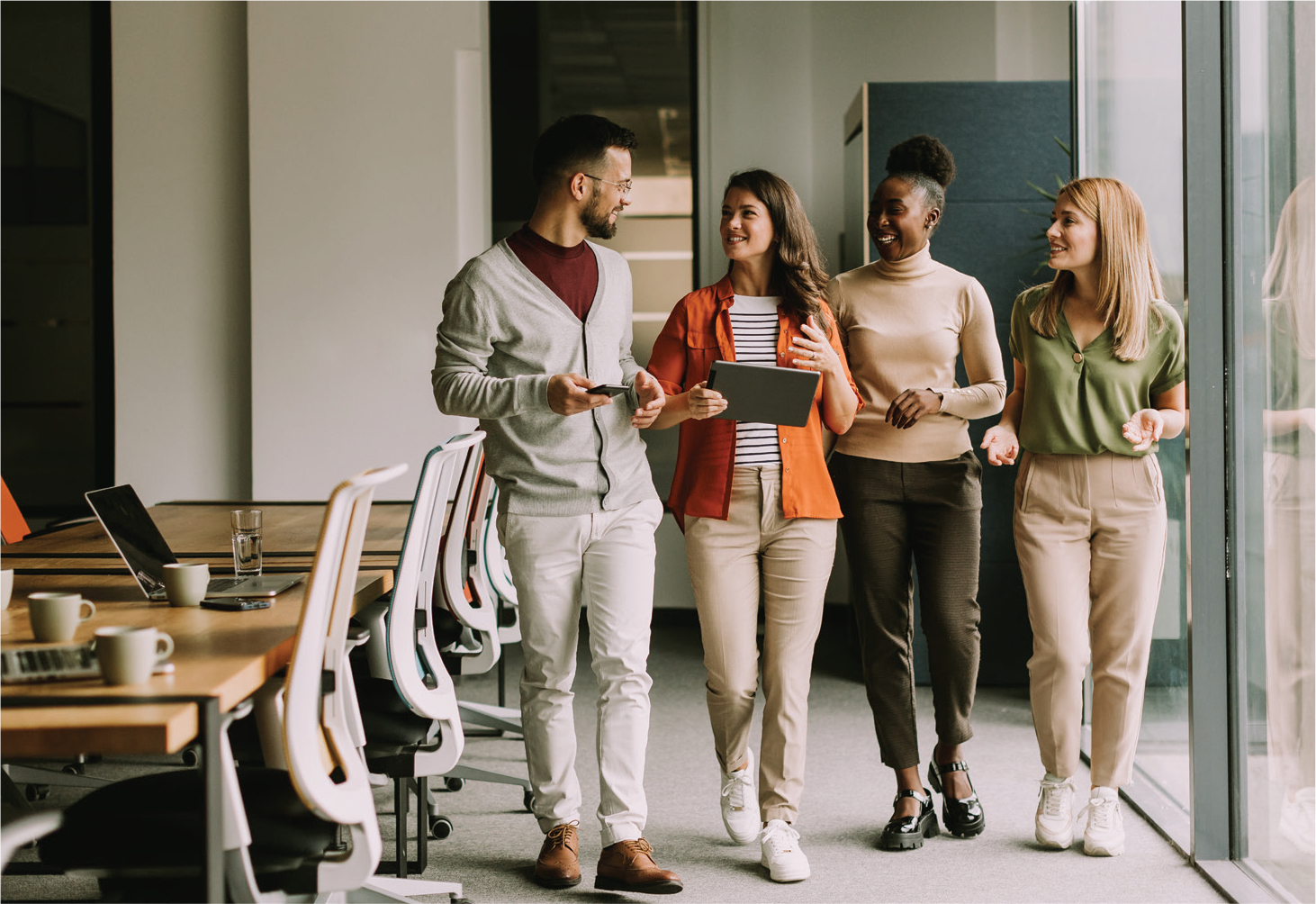 Photograph of a group of coworkers chatting convivially in an office hallway
