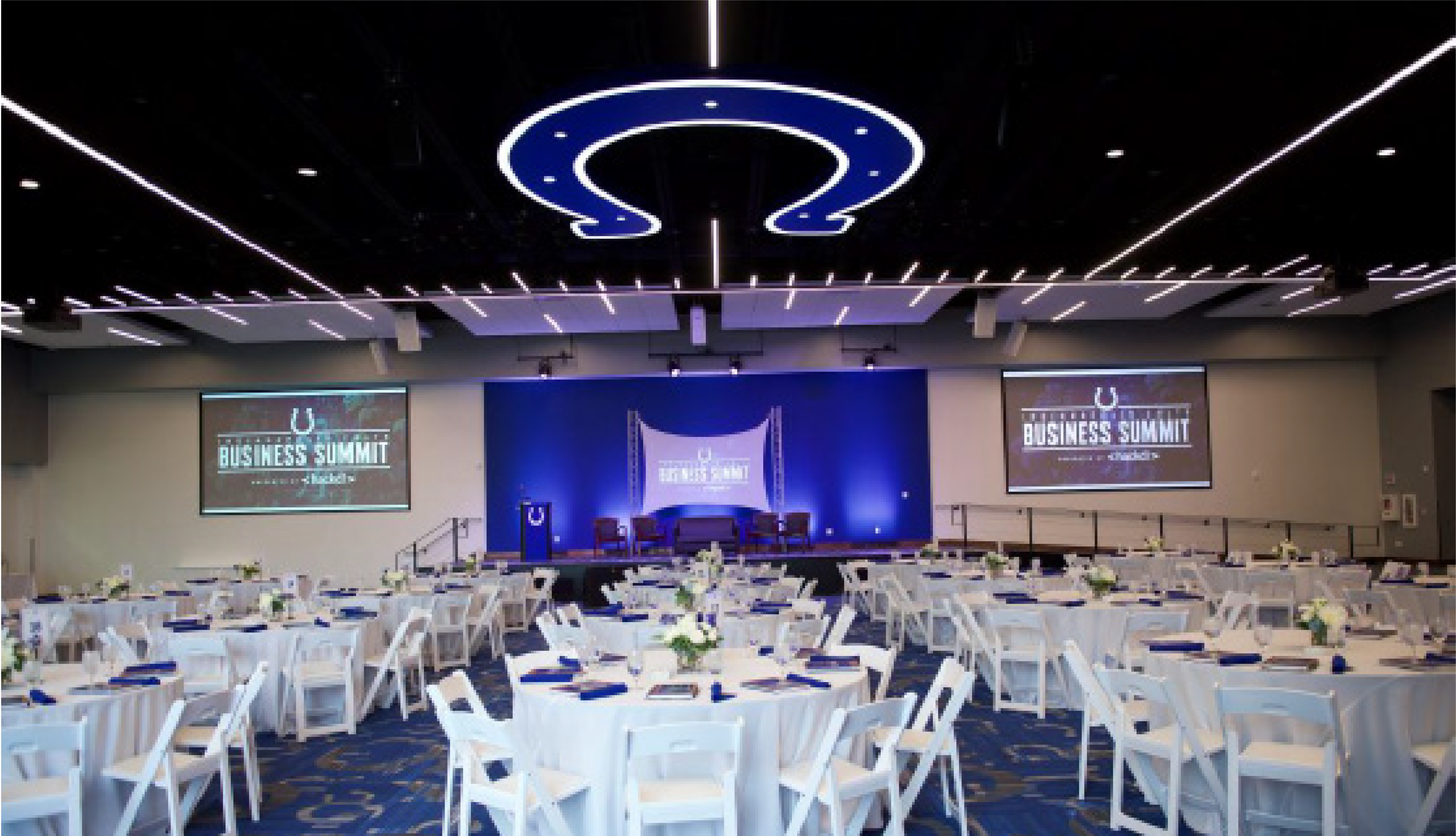An Indianapolis Colts themed event space set up with round tables in a blue and white color scheme