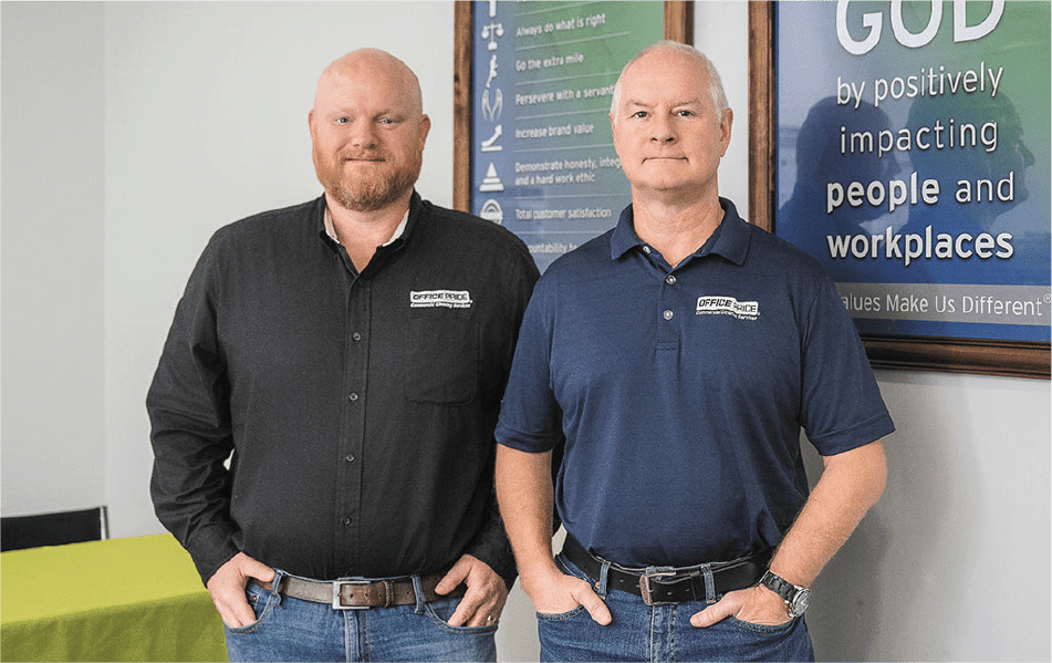 2 members of CKM Enterprises LLC posed in front of framed posters