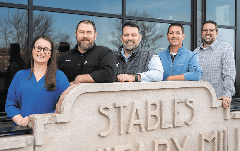 5 members of Inherent Commercial LLC posed behind a concrete sign
