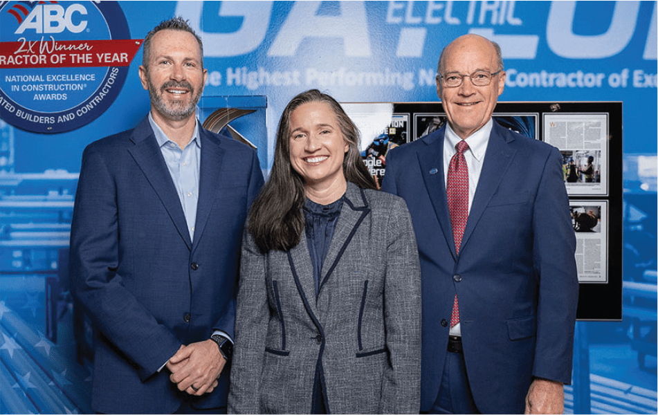 3 Members of Gaylor Electric posed in front of a Gaylor Electric themed mural