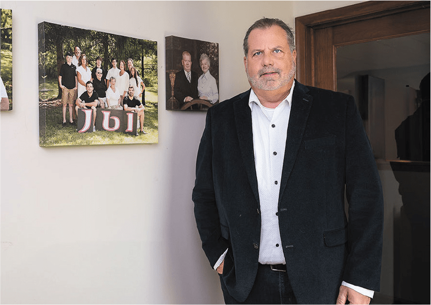 A member of James Babcock Inc posed in front of family photos