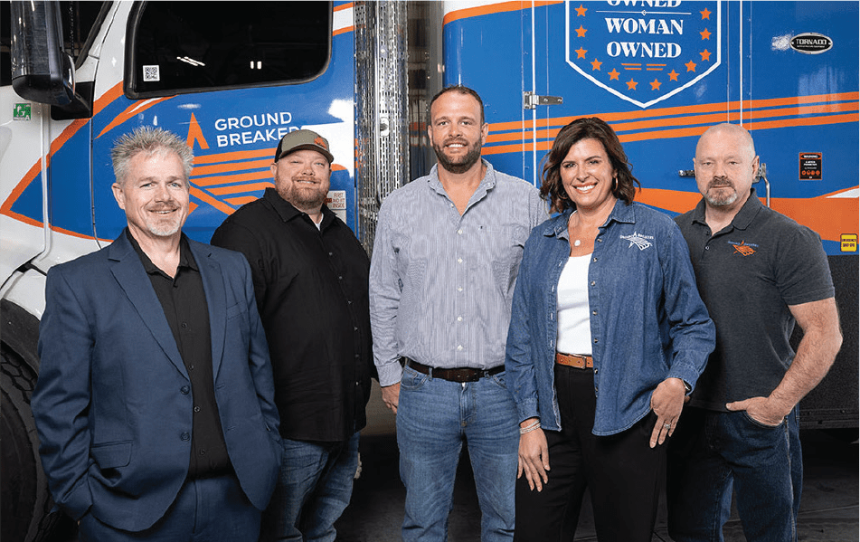 5 members of GroundBreakers posed in front of a semi truck