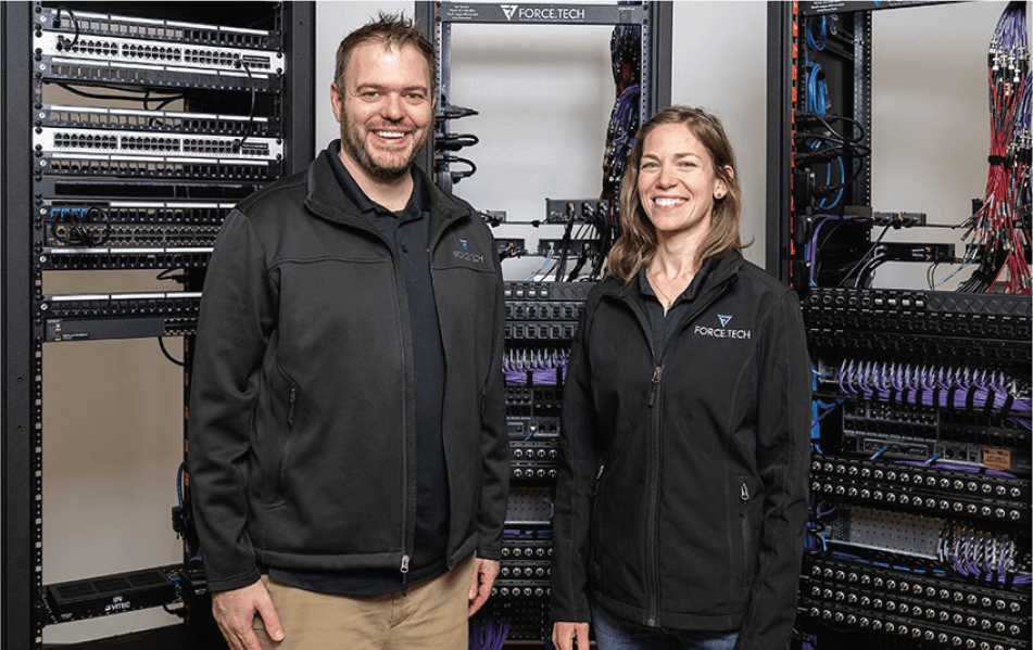 2 members of Force Tech posed in front of server racks