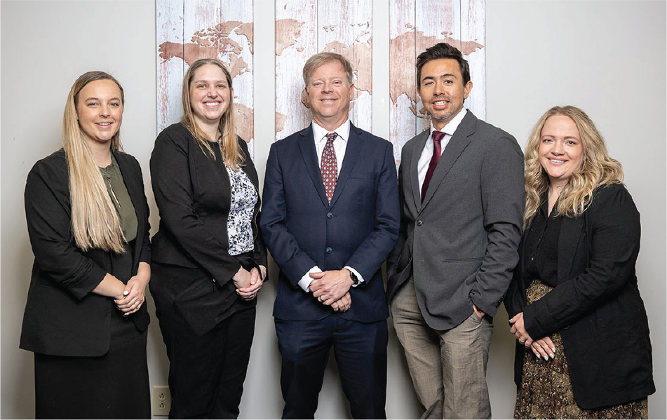 5 members of Flora Legal group posed in front of a world map
