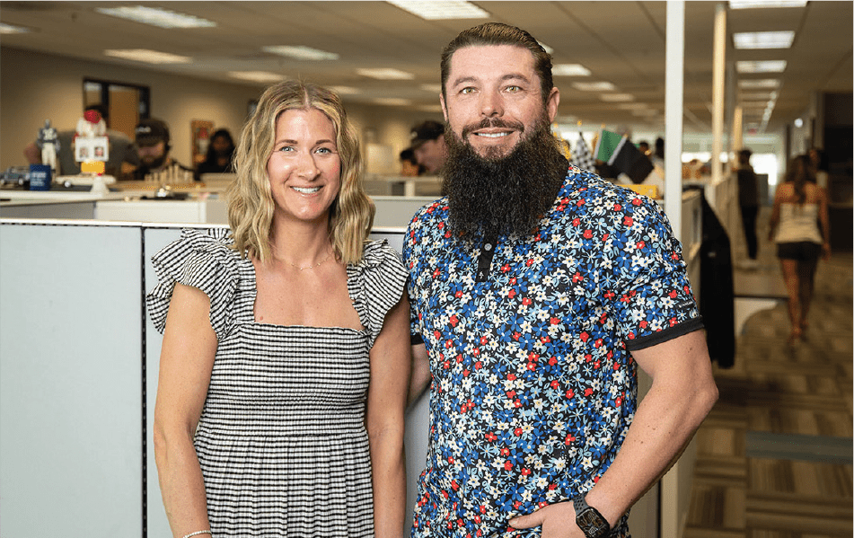 Two members of Koola Logistics posed in front of a cubicle