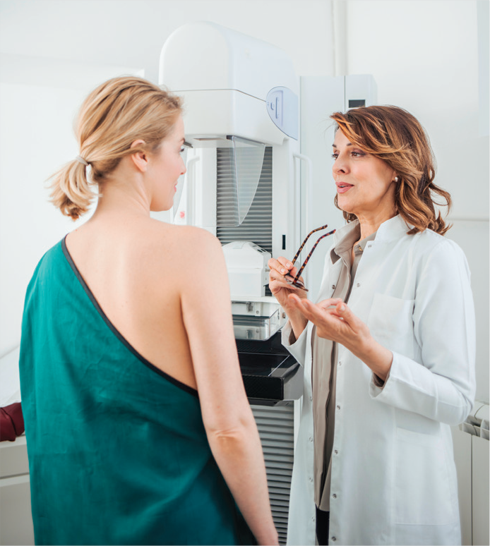 A woman speaks with a doctor in preparation for a mammogram